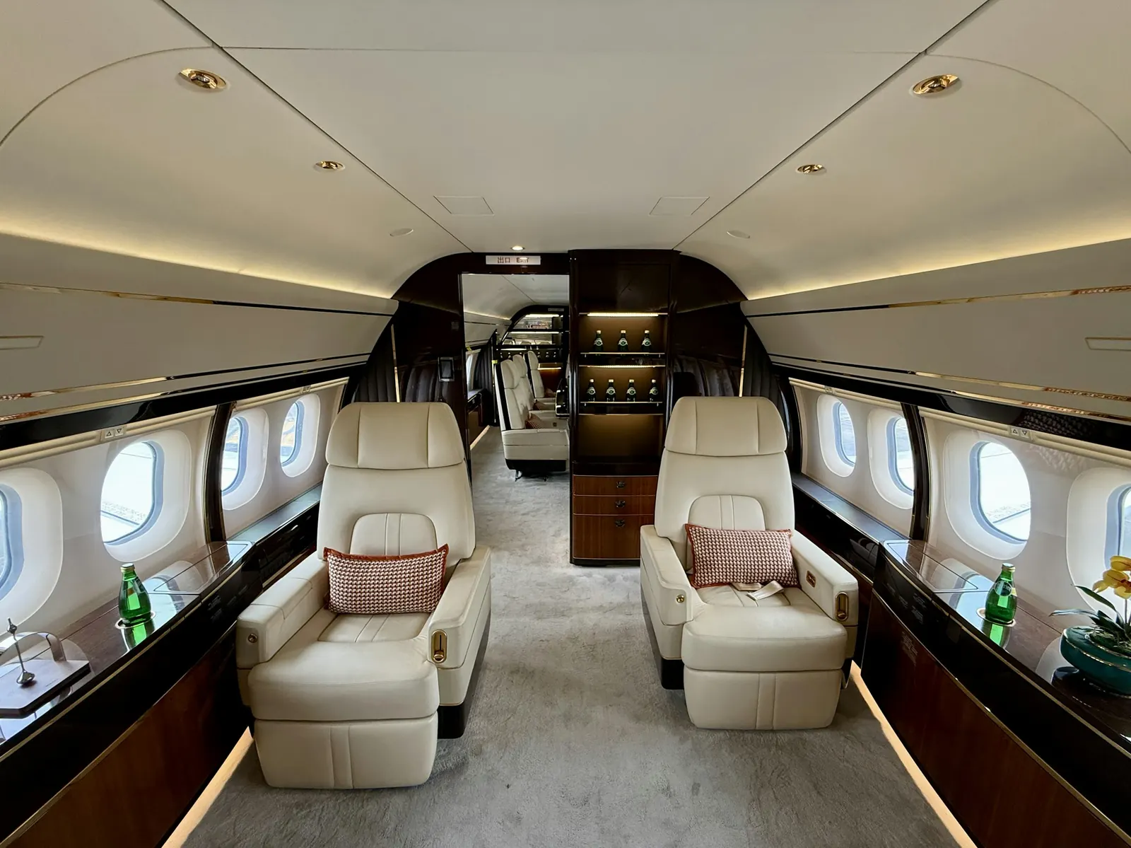 Wide private jet cabin with cream leather seats and polished wood